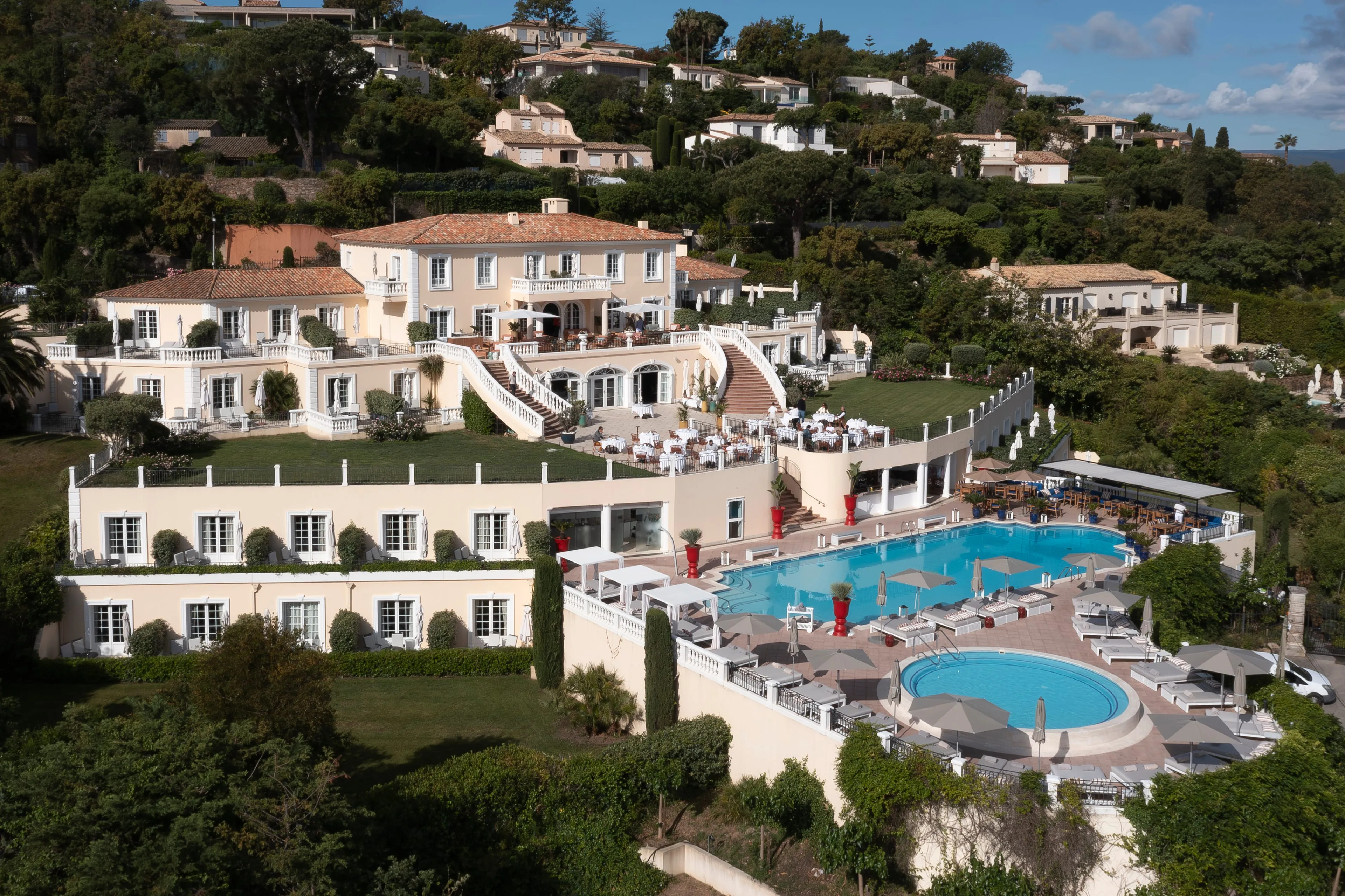 Villa Belrose in Gassin from the air, mimosa-yellow façades and cascading terraces above the pool and the Bay of Saint-Tropez